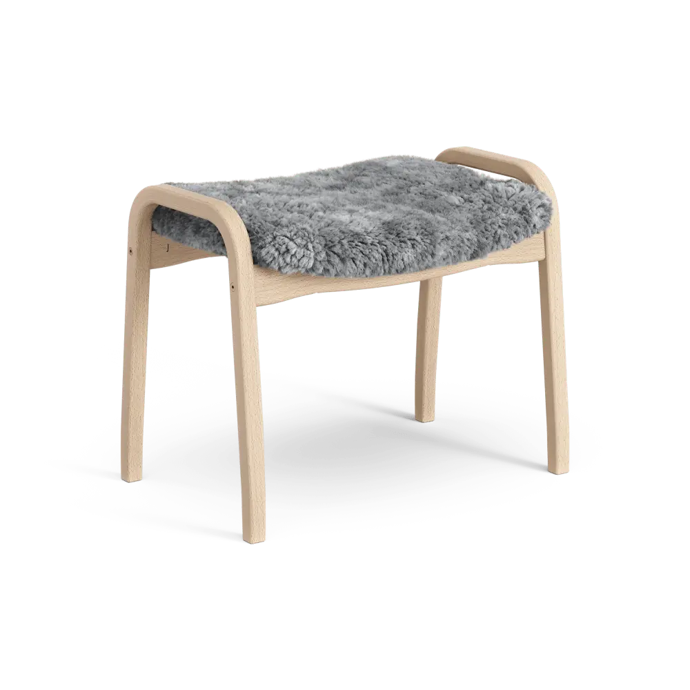 Lamino-Fußhocker | Swedese | Lundia Living: Stilvoller Komfort dank hellem Holzrahmen und weichem, grauem Schaffellsitz.