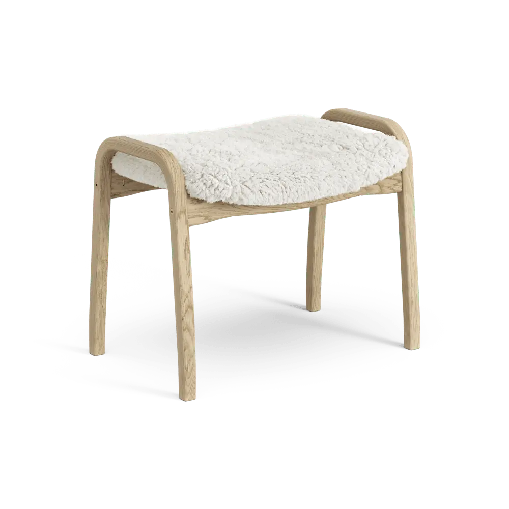 Lamino-Fußhocker | Swedese | Lundia Living mit einem geschwungenen Holzrahmen und einem weichen, weißen Schaffellsitz für entspanntes Sitzen.