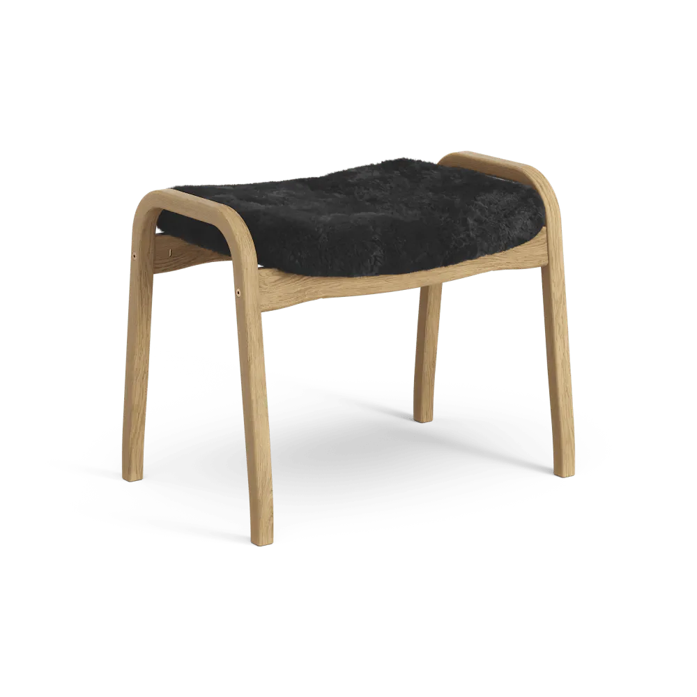 Lamino-Fußhocker | Swedese | Lundia Living: Mit geschwungenem, hellem Holzrahmen und weichem, schwarzem Schaffellsitz für eleganten Komfort