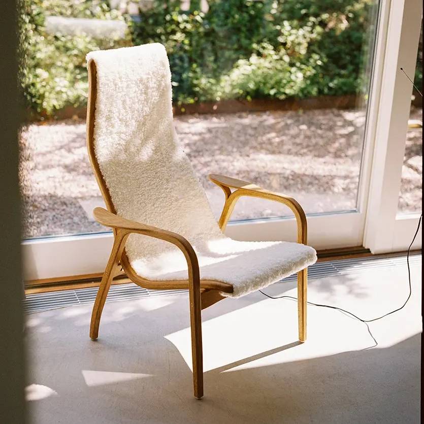 Lamino Sessel | Swedese | Lundia Living mit geschwungenem Holzrahmen und weichem, weißem Bezug in hellem Interieur