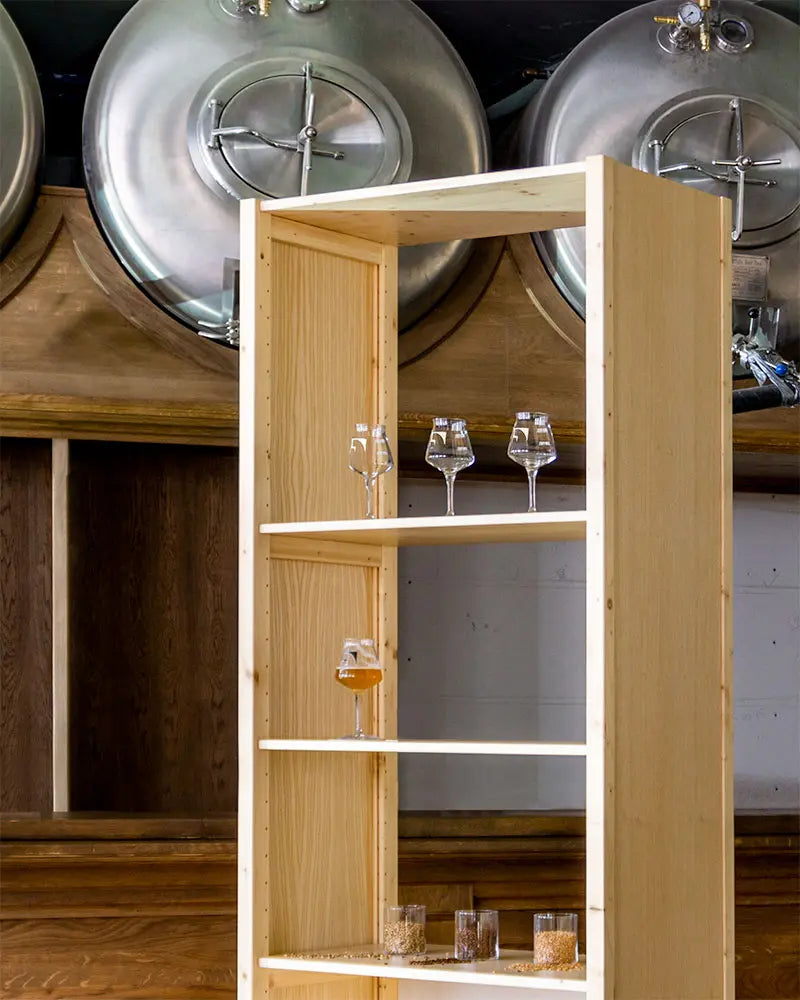 Open houten kast met meerdere glazen gevuld met bier en korrels, voor grote roestvrijstalen brouwketels