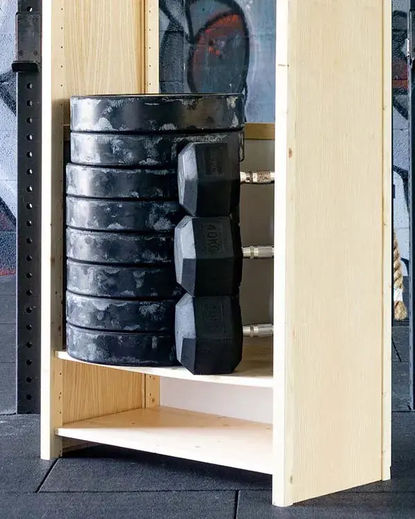 Open houten kast met stapel zware zwarte gewichten en drie hexagonale dumbbells in sportschoolomgeving