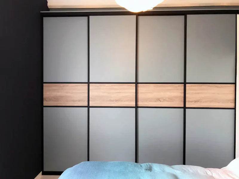 Strak design van een kast met matgrijze deuren en een houten strook in het midden tegen een donkergekleurde muur.