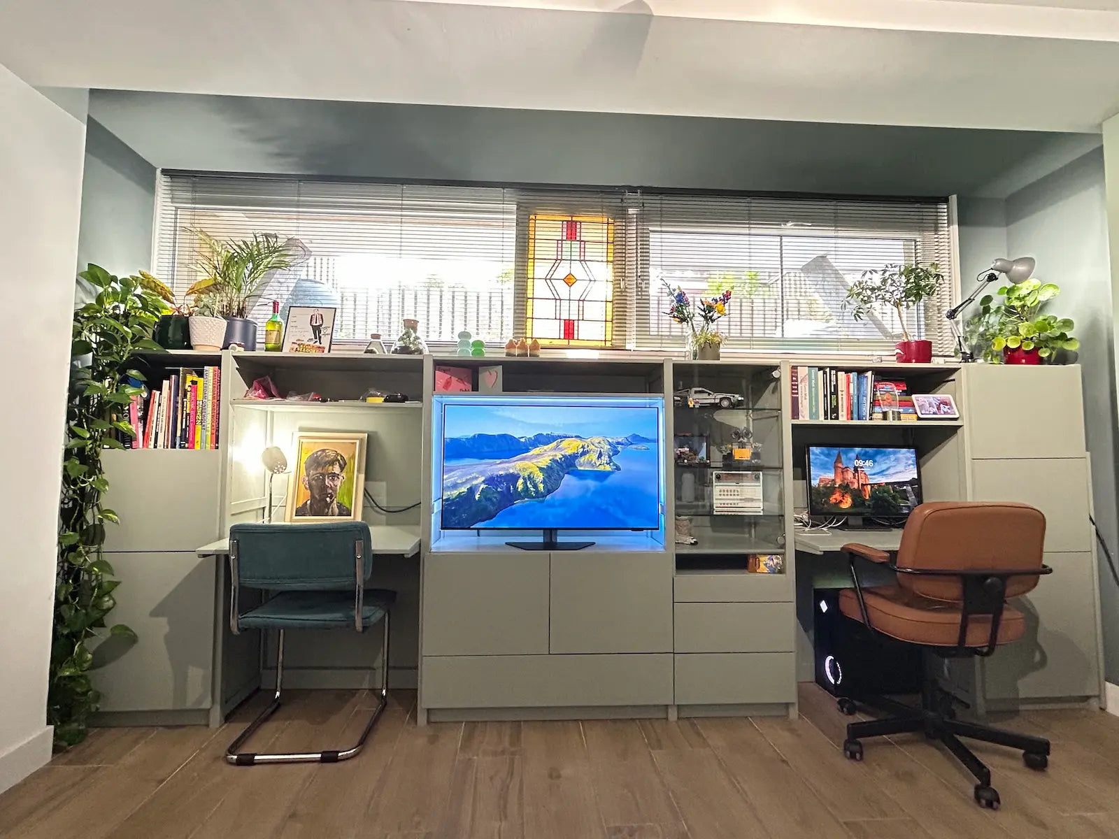 Lichte werkplekken met groene en bruine stoelen, planten, boeken, kunstobjecten en twee beeldschermen in kastopstelling.