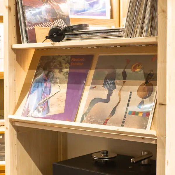 Houten plank met vinylplaten, een koptelefoon en een draaitafel in warme sfeerverlichting