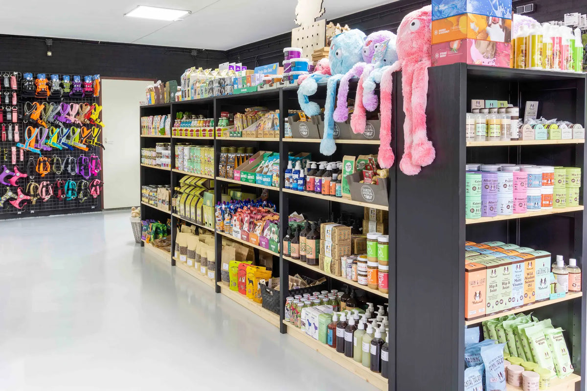 Lichte winkelruimte met zwarte rekken vol verpakte producten en kleurrijke pluche knuffels aan de zijkant